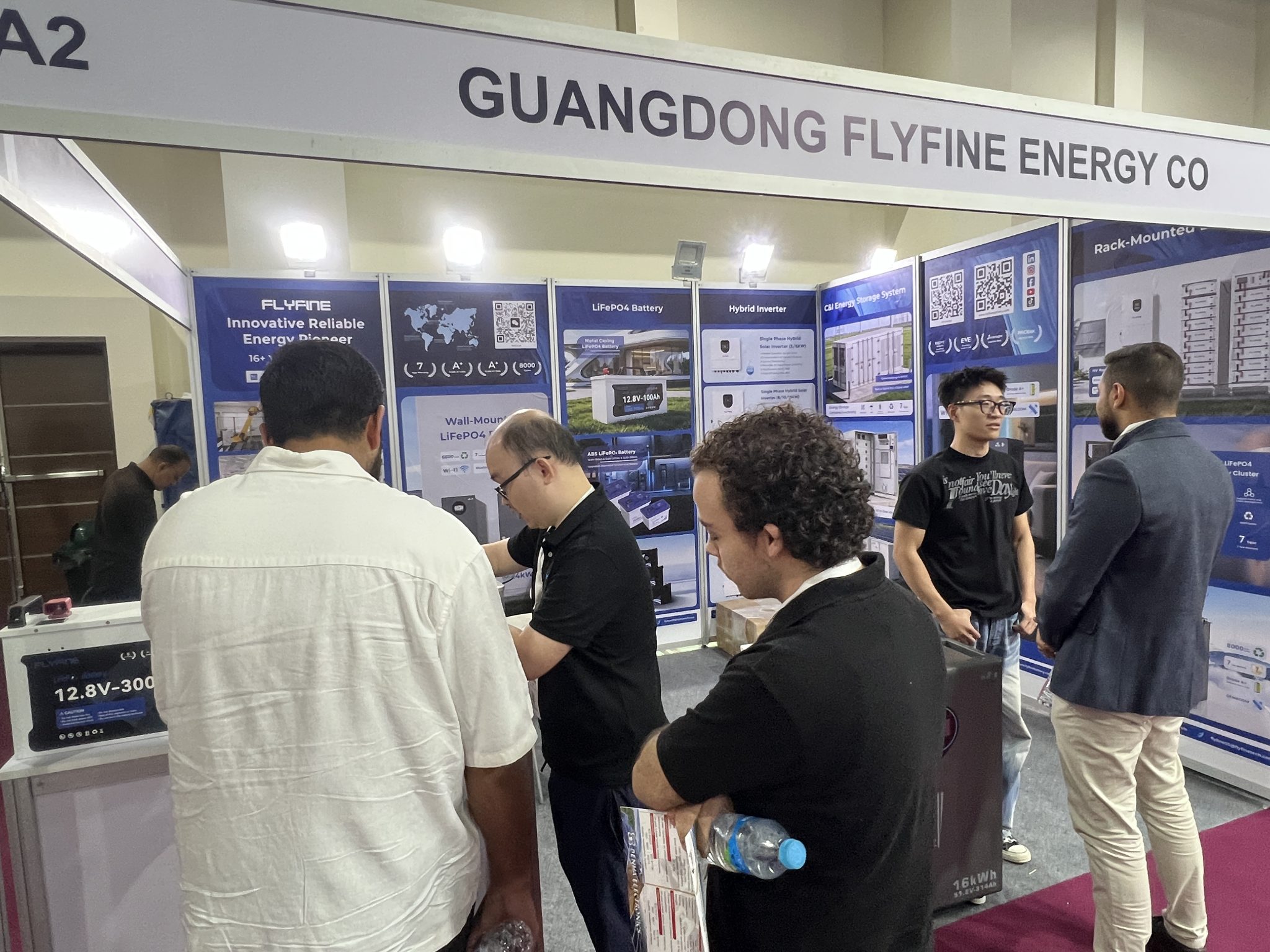 FLYFINE exhibition booth showing LiFePO4 batteries and hybrid inverter solutions